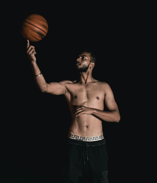 Man performing a controlled strength exercise in a minimalist dark room.